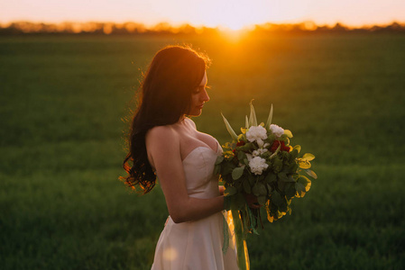 日落时手捧花束的新娘肖像