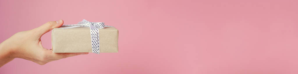 妇女的手持有粉红色背景礼品盒, 横幅与复制空间