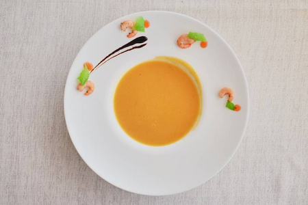 蔬菜奶油汤配胡萝卜白碗。在粗糙的白色布的顶部视图。健康饮食膳食