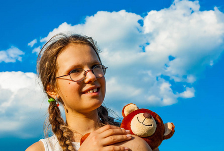 快乐的孩子在暑假。天空背景玩具的年轻女孩肖像