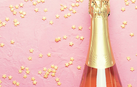 圣诞节或新年粉红色背景与瓶起泡酒, 玫瑰香槟和黄金装饰, 顶部视图