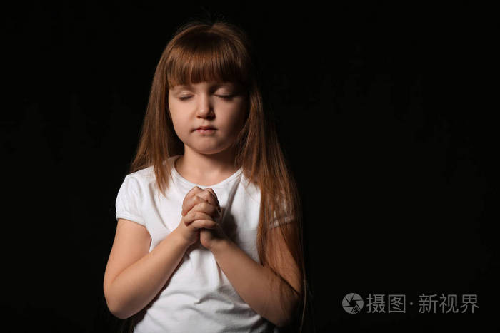 宗教基督徒女孩在黑色背景下祈祷