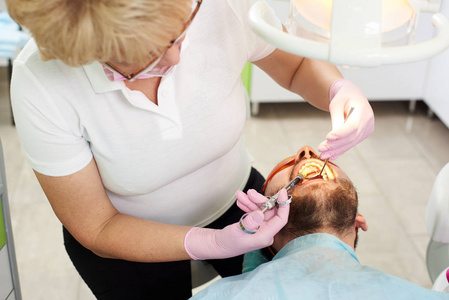 牙医妇女在病人的口中做麻醉注射。现代牙科门诊麻醉牙的注射技术