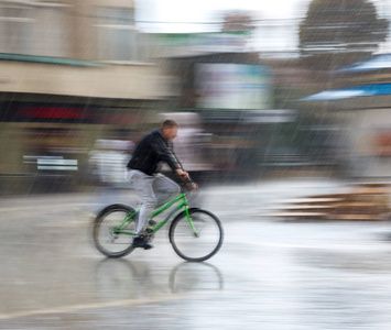 骑自行车的城市道路上雨天在运动模糊