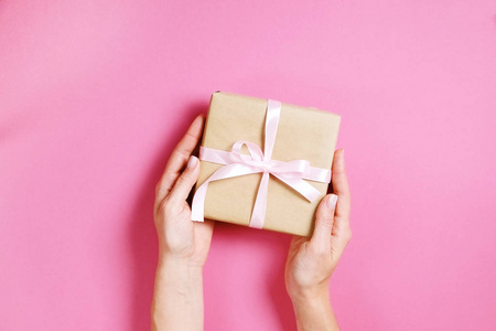在老式工艺包装纸中, 手捧着生日礼物的女性手中的特写。Femenine 构成与礼物在妇女的胳膊