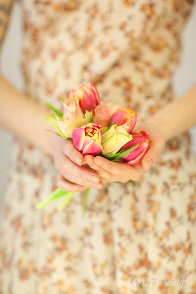 女人手捧着春天的花朵, 郁金香和玫瑰花, 春天的花朵礼服, 感性的工作