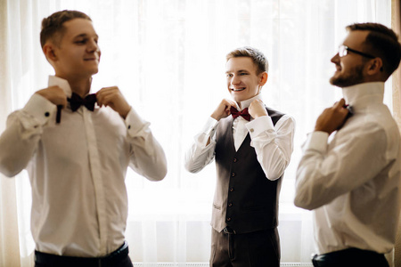三个英俊的男性朋友见面和取悦彼此。伴郎或最佳人问候新郎在婚礼那天