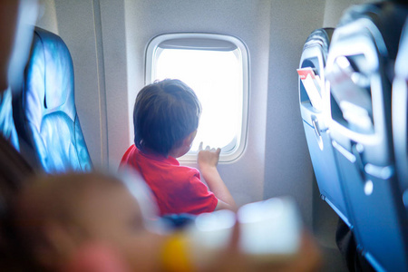 在飞机上飞行的小男孩看在飞机窗口外面