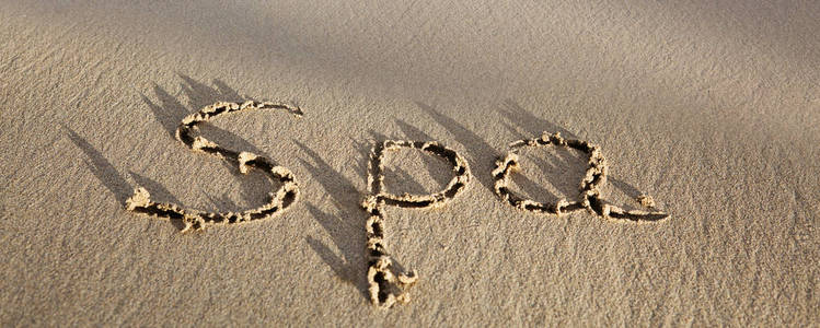 文字水疗写在海边的沙滩上。度假理念