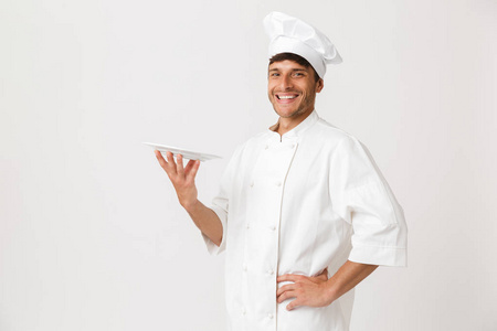形象的开朗英俊的年轻厨师站在白色墙壁背景保持板查出的人