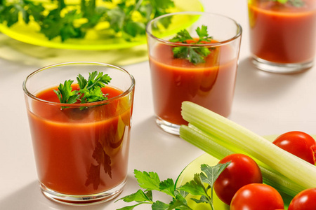 三杯番茄汁, 用欧芹或香菜叶装饰。接下来是一盘欧芹, 西红柿和芹菜茎