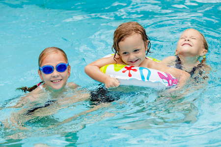 游泳池里的两个男孩两个小女孩和小男孩在游泳池里玩照片