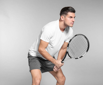 在灰色背景下打网球的英俊男子肖像