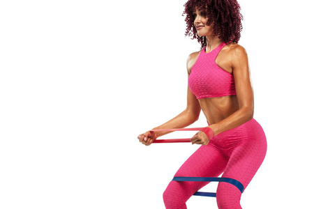 肌肉年轻适合运动妇女运动员在粉红色运动服与乐队或扩张器在健身房。健身营养广告复制空间