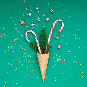 新年圣诞节圣诞佳节聚会庆祝华夫饼锥糖手杖冷杉树枝复制空间绿彩纸背景。方形模板贺卡2019