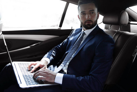 使用笔记本电脑坐在车里的商人