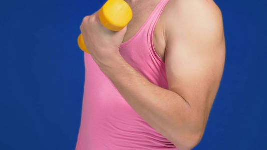 一个穿着粉红色背心的男人, 有深领口和毛茸茸的胸部, 做哑铃印刷机.