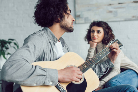 男友在家里为女朋友弹奏声学吉他