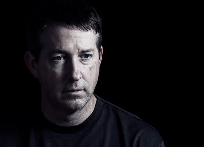 成熟的男人在黑暗的背景表达负面情绪照片