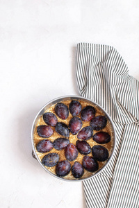 秋天烘烤概念未加工的李子 piein 金属模子在皱巴巴的条纹餐巾。顶部视图, 平躺, 复制空间。最小图片