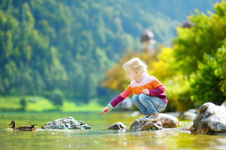 可爱的女孩在德国 konigssee 湖在温暖的夏日玩耍.