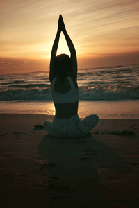 运动的年轻女子在沙滩上做瑜伽练习