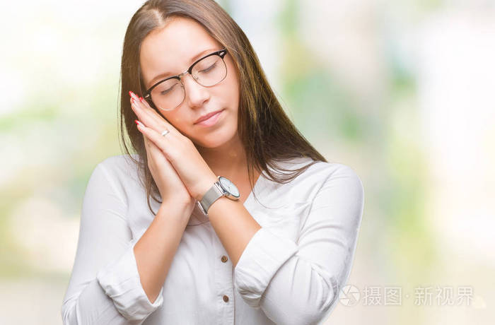 戴眼镜在孤立的背景睡觉疲惫的梦和摆姿势双手在一起而微笑着闭着眼睛