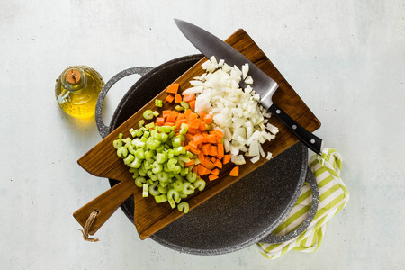 在木制砧板上切碎的蔬菜和厨师的刀。餐厅或家常菜的基本切割。和炒锅