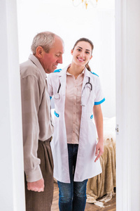 站在一个房间旁边的年轻的微笑护士的老人的侧面视图