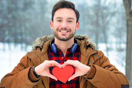 美丽的男孩用亲切的微笑给予爱他的心作为礼物照片