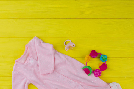 柔软的粉红色婴儿女孩布与奶嘴和拨浪鼓