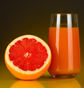 在玻璃和它旁边暗橙色背景上的柚子美味葡萄柚汁