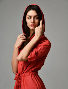 年轻美丽的女人摆在新的红色时装服装与裤子和遮光罩