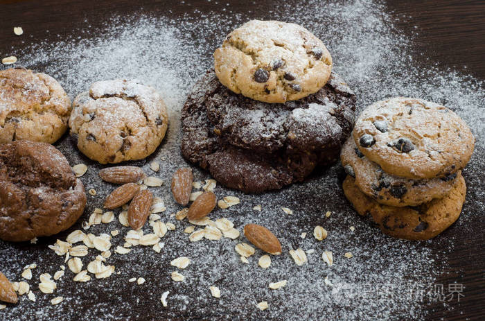 饼干与巧克力在黑暗的背景下, 糖粉, 燕麦片, seasame 和杏仁