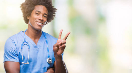 黑人美国外科医生的人在孤立的背景微笑与快乐的脸眨眼在相机做胜利标志。第二个