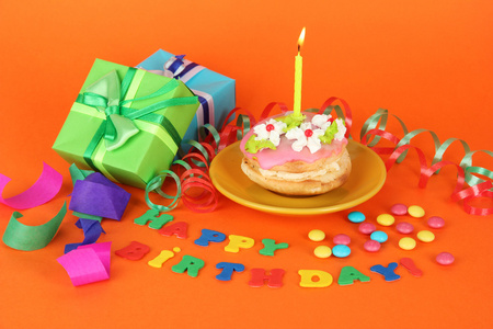 七彩生日蛋糕与蜡烛和礼品的橙色背景