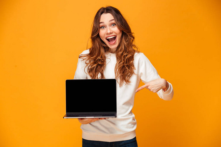 惊奇的愉快的妇女在毛衣显示空白笔记本电脑屏幕