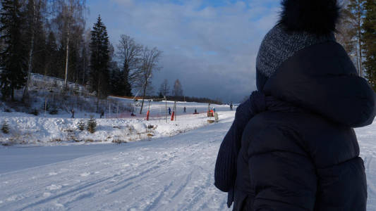 一个英俊的蹒跚学步的男孩 儿子 走过滑雪胜地的雪地, 在一个晴朗的日子里, 在冬天, 所有的雪