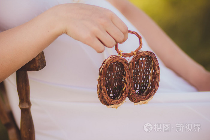 蛇蝎 enceinte et chaussons，特写的针织的婴儿鞋在她的肚子，孕妇侧视图