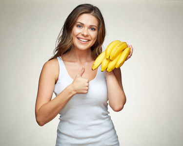 微笑的女人手里拿着黄色的香蕉，在米色的背景上显示出来的拇指