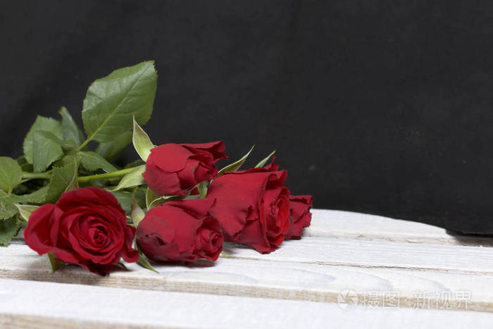 花束的猩红玫瑰.五朵花躺在木盒子上.在黑色背景下