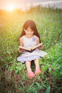 小可爱的亚洲女孩读书在自然图片