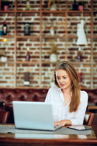 女实业家坐在自助餐厅时使用笔记本电脑工作