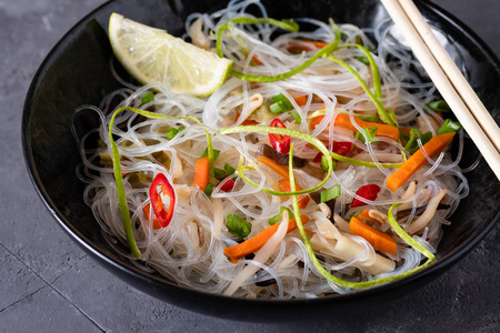 越南面条汤。辣椒, 米粉, 豆芽, 在黑色的背景下拿起筷子