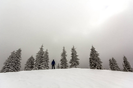 男子徒步登山者站在冰雪覆盖的高山上欣赏风景