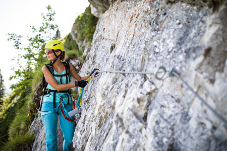 漂亮的, 女性登山者通过 ferrata 攀登在岩石上照片