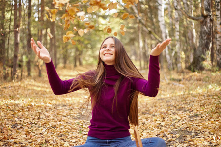 迷人的女孩玩秋叶。青少年在秋季公园阳光明媚的一天的肖像
