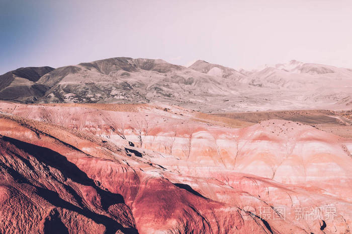 在阳光明媚的天空下五颜六色的粉红色丘陵柔和的颜色的岩石和山