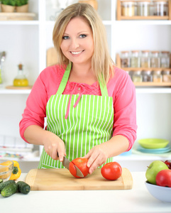 幸福微笑的女人，在厨房里，她手里拿着新鲜的蔬菜