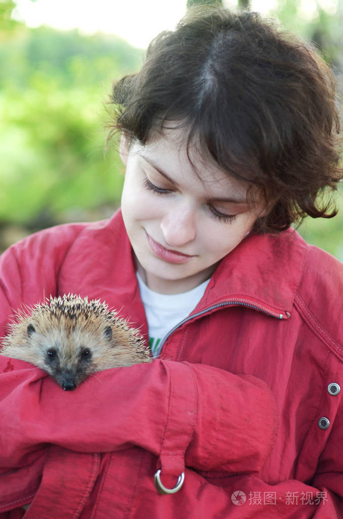 女孩握着一个小刺猬在她的手和微笑